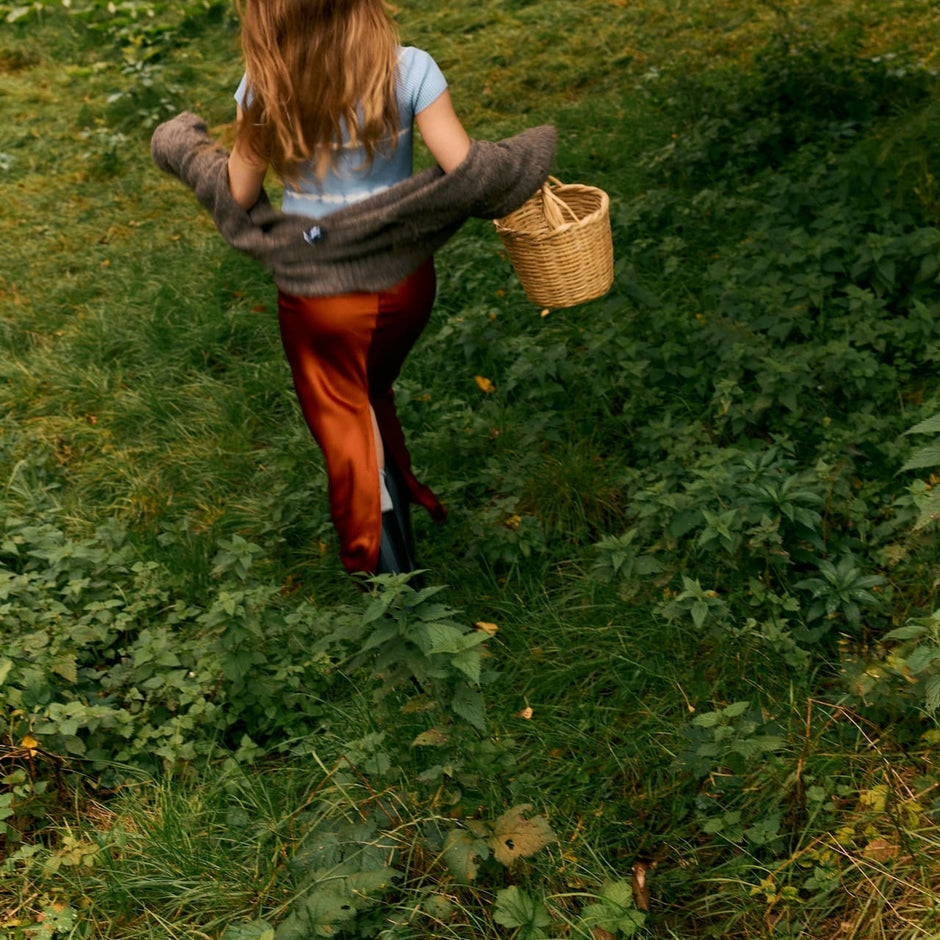 woman in red dress walking through autumn leaves, hair blowing in wind
