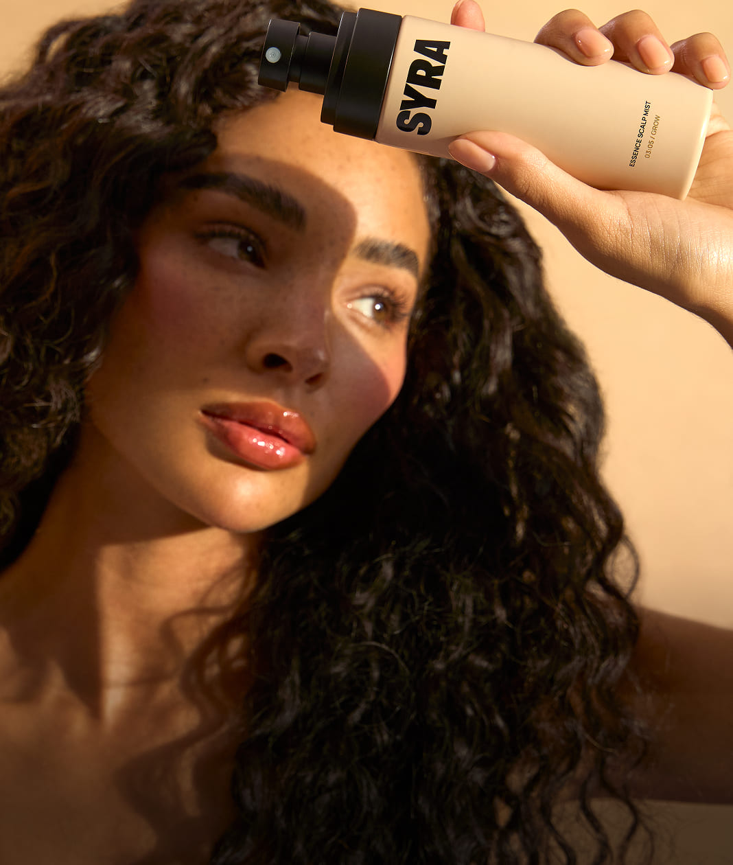 Person holding a SYRA product near their face with a warm background