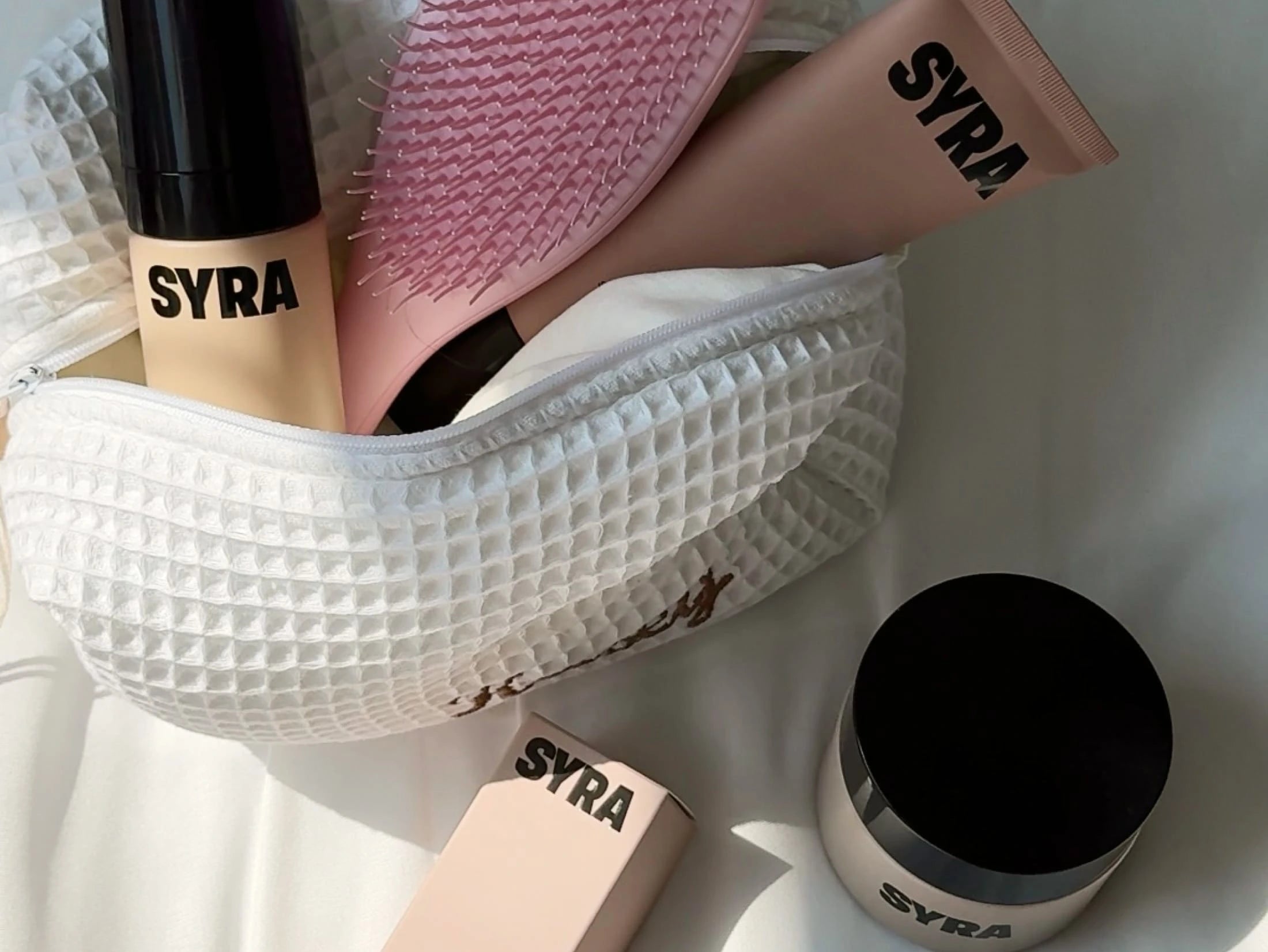 Bundle of syra products on a bed in a wash bag