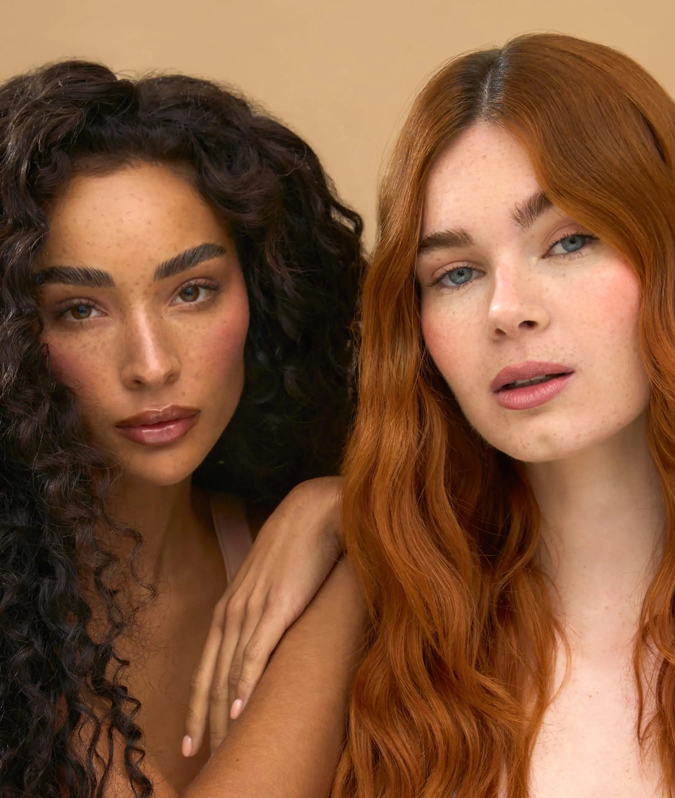 Two women with different hair colors against a beige background